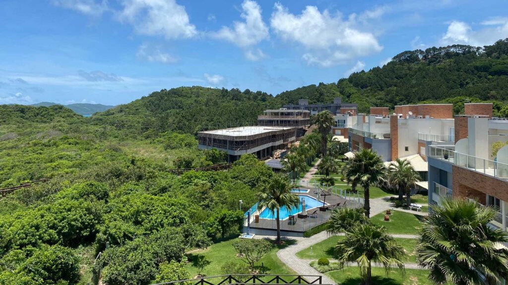 Vista de construção de apartamentos com piscina cercada por árvores