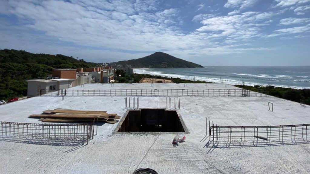 Montanha ao centro, mar a direita e prédio a esquerda vistos do topo de um prédio em construção